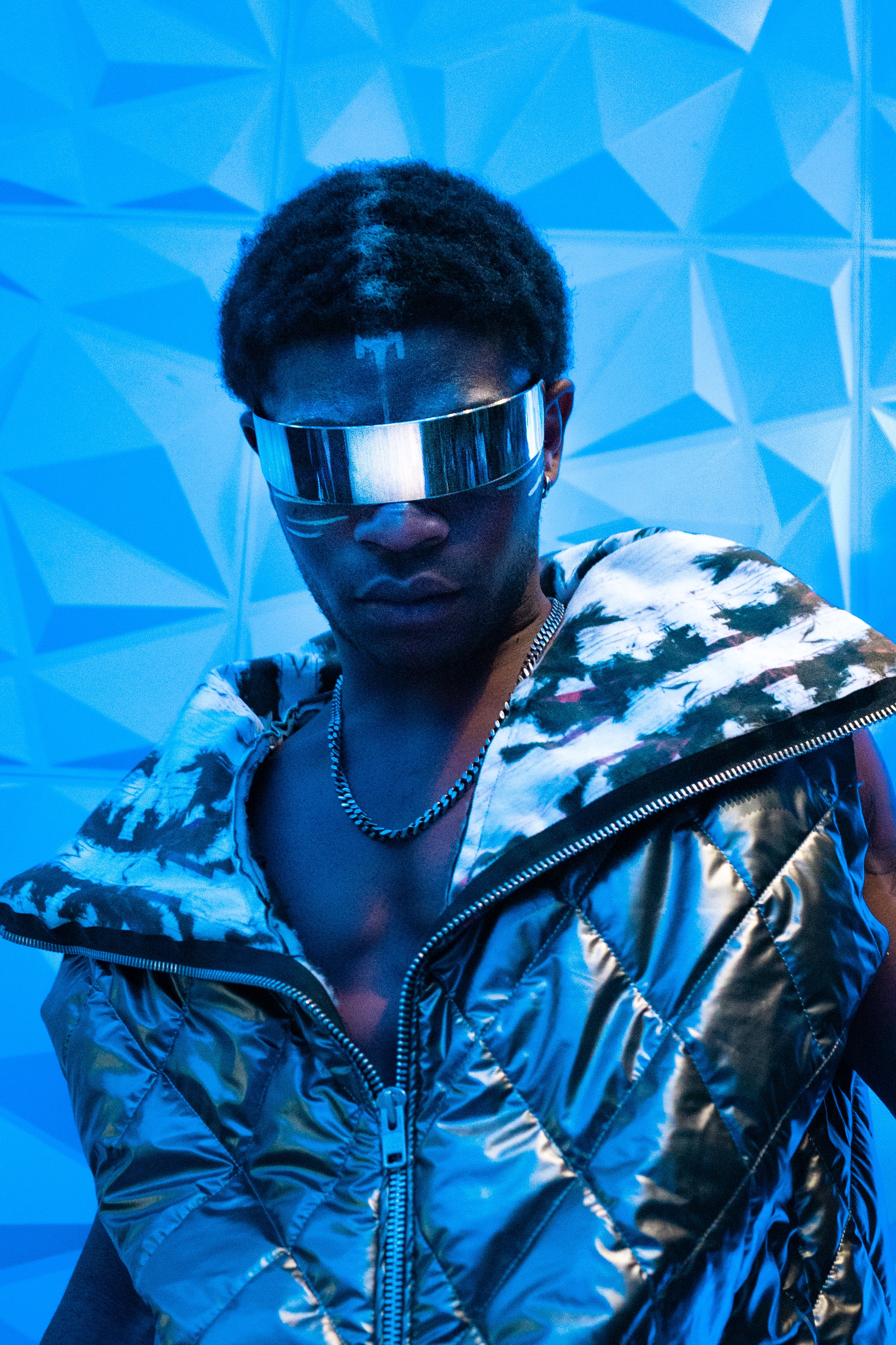 Person wearing a reflective jacket and silver visor against a blue geometric background