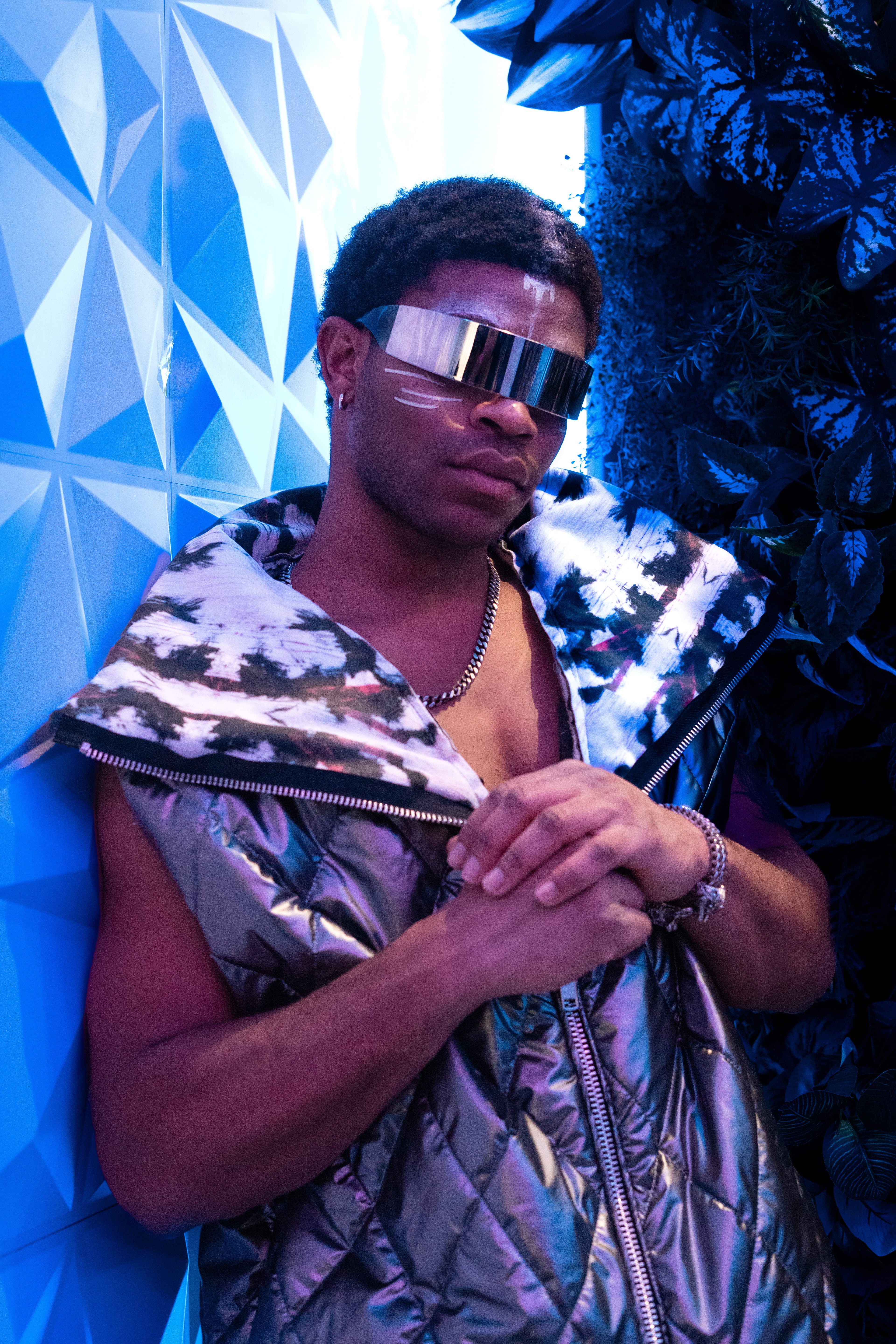 Person wearing a reflective outfit with a blue geometric background