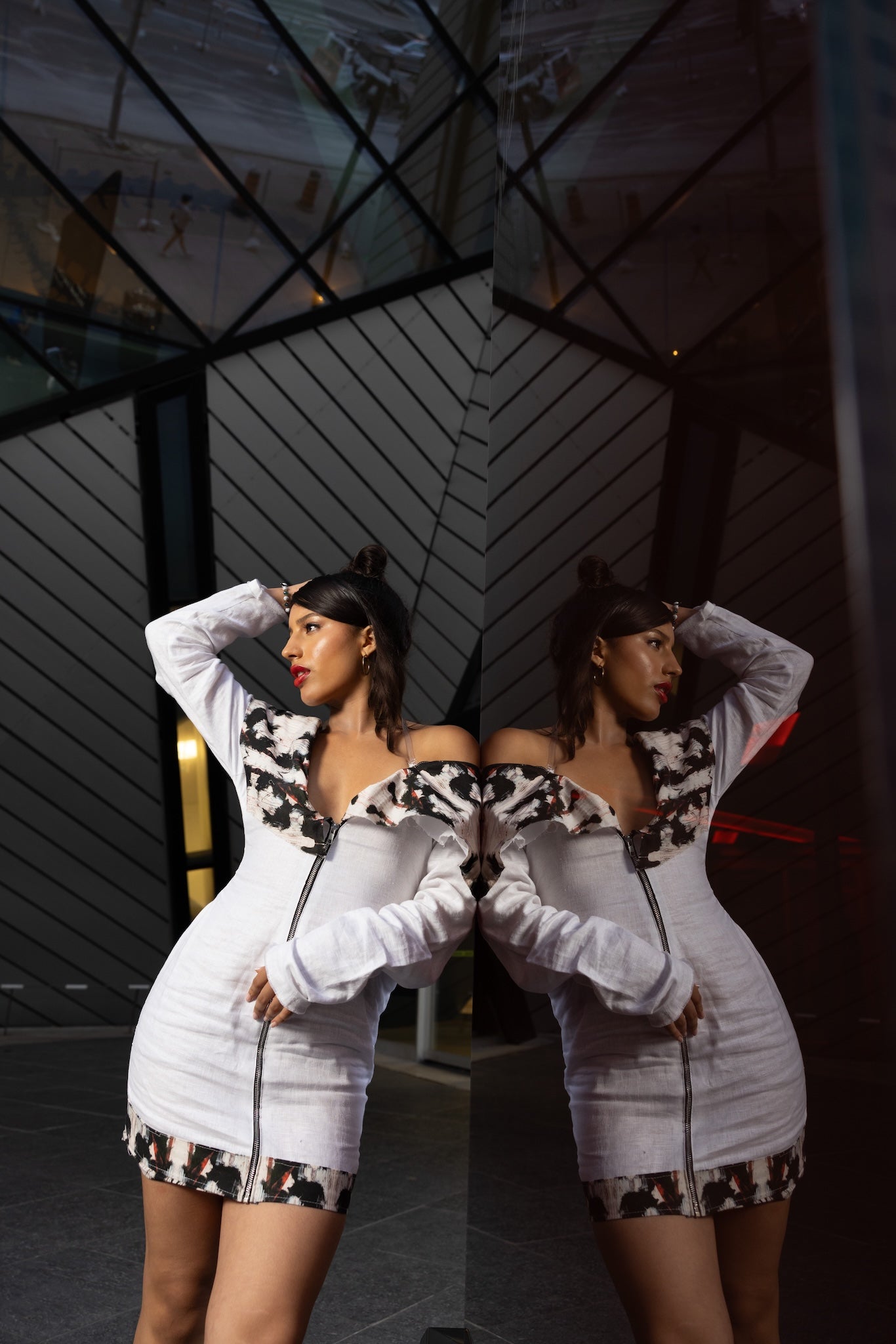 Woman in a white outfit with animal print details posing in front of a building.