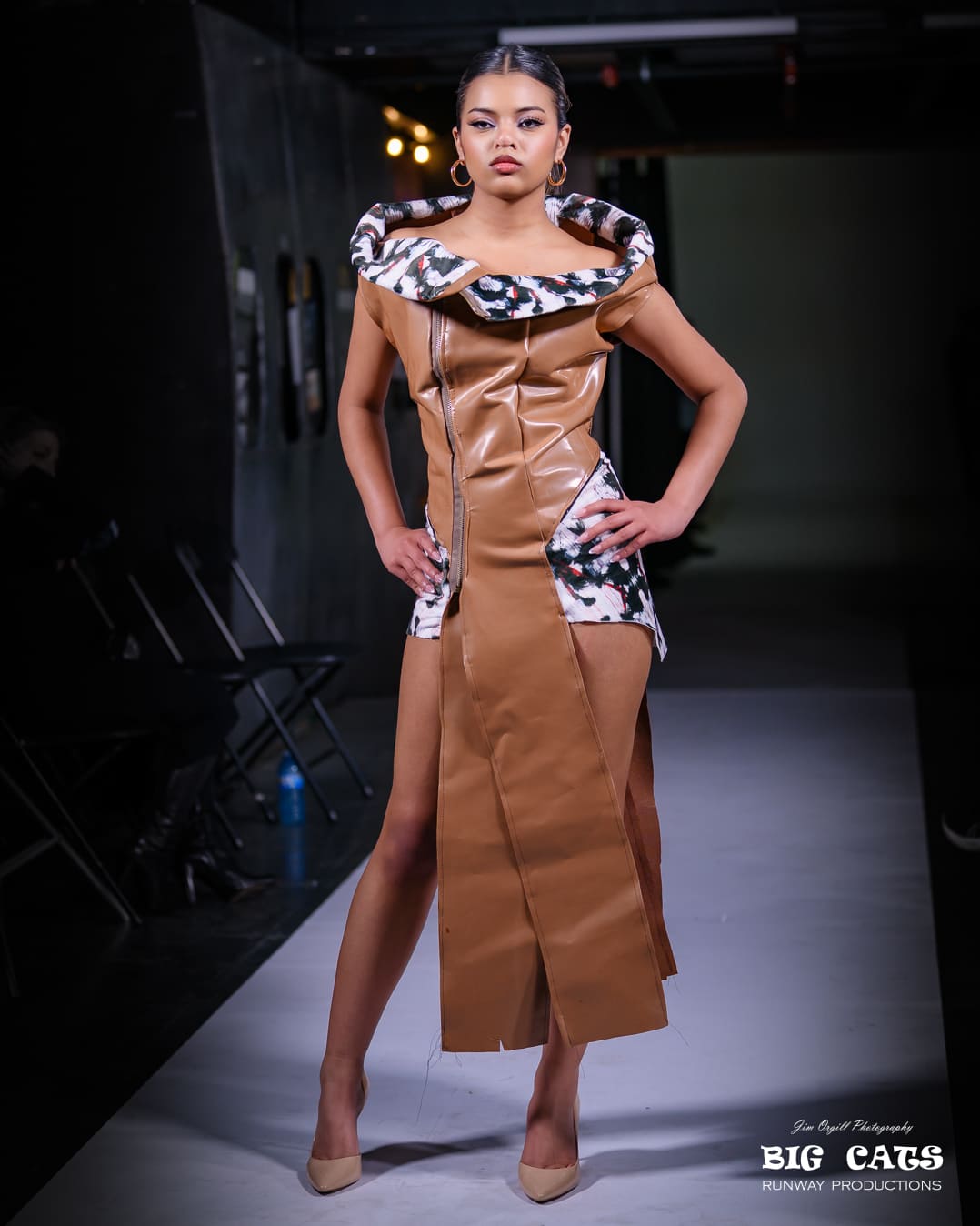 Model wearing a brown dress with a patterned collar on a dark background