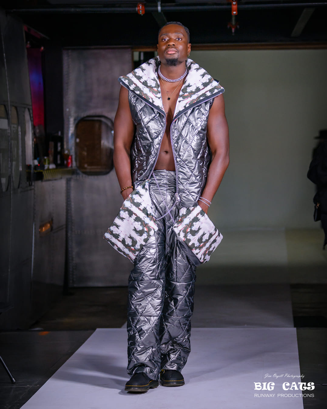 Man wearing a silver quilted outfit on a runway with 'Big Cats' branding.