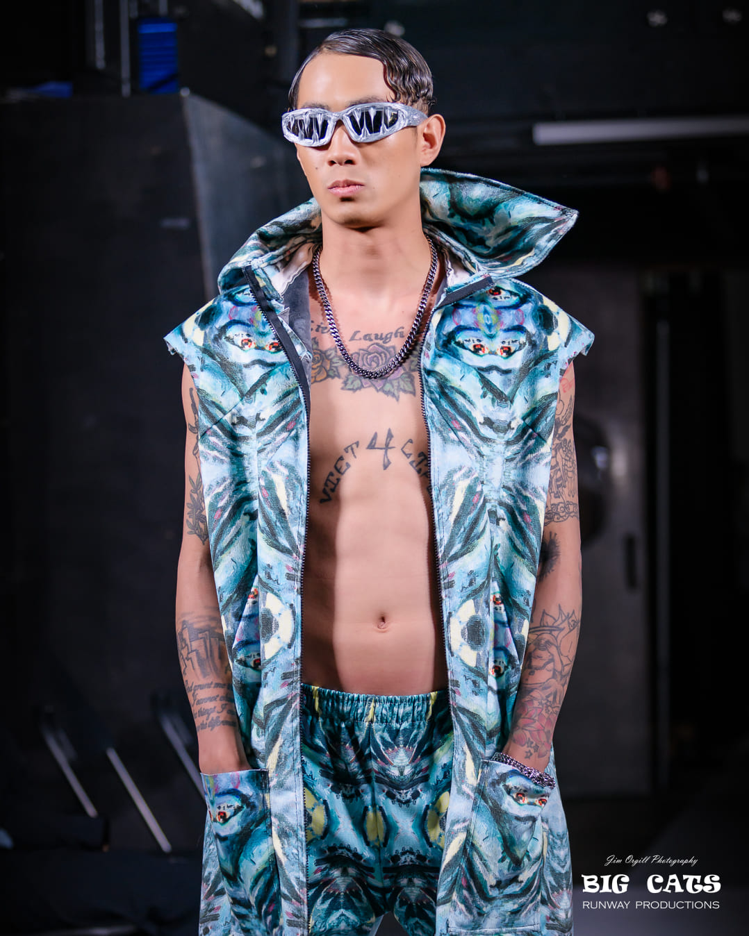 Model wearing a patterned outfit with 'Big Cats' branding on a dark background
