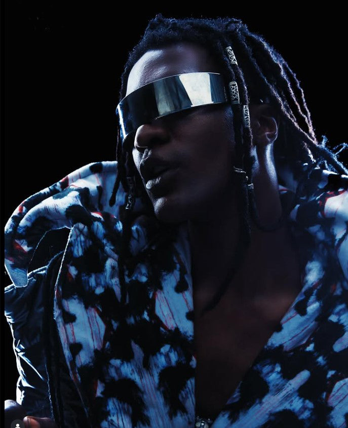 Person wearing a patterned jacket and reflective visor against a dark background