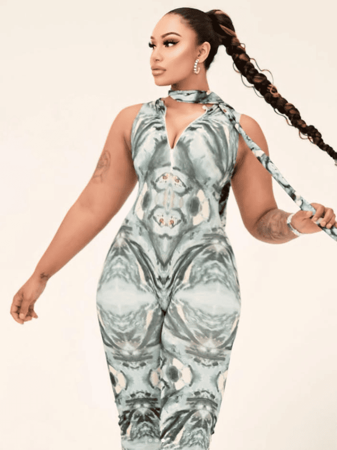 Woman wearing a patterned jumpsuit with a scarf, on a plain background