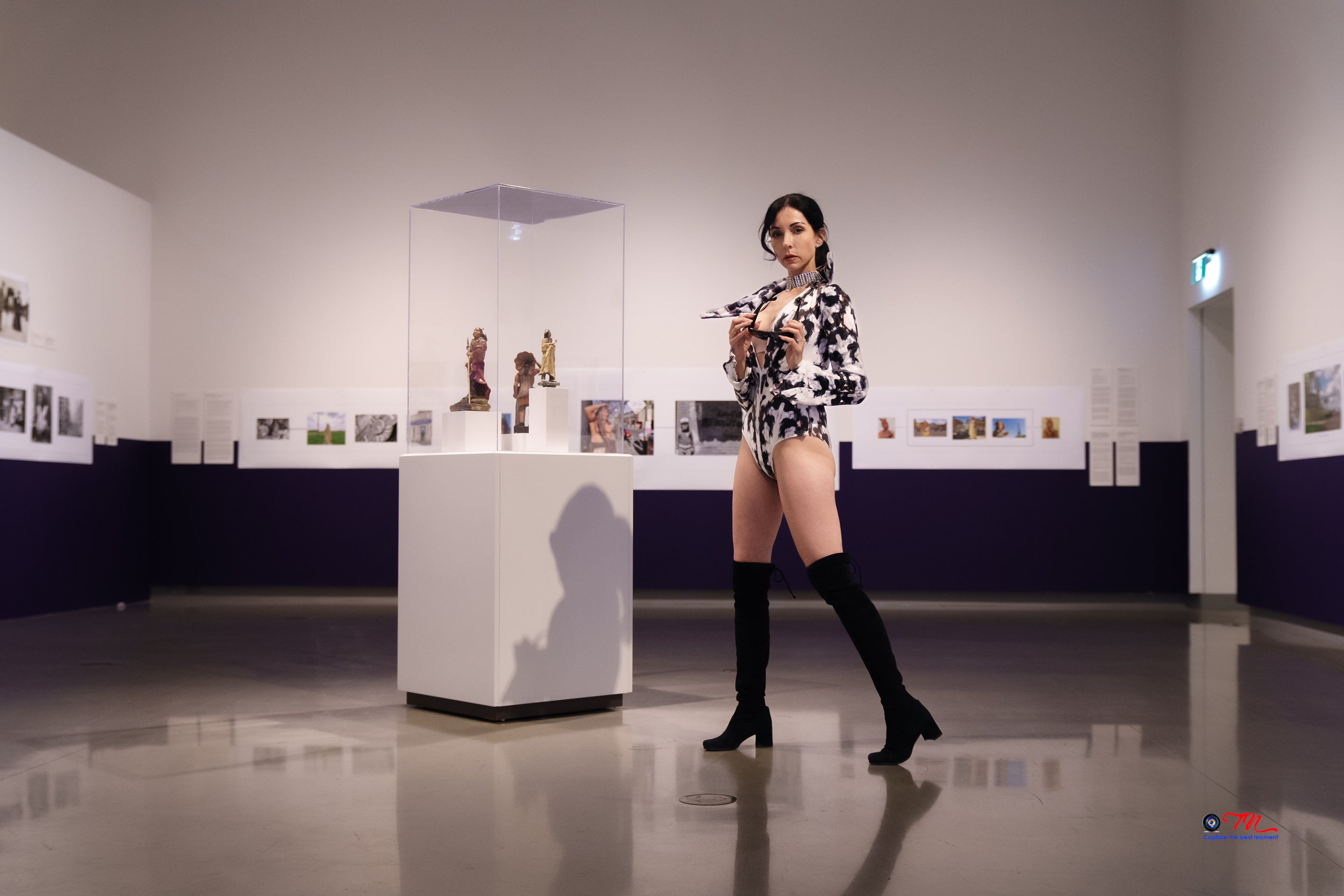 Woman in a stylish outfit standing in an art gallery with sculptures on display.