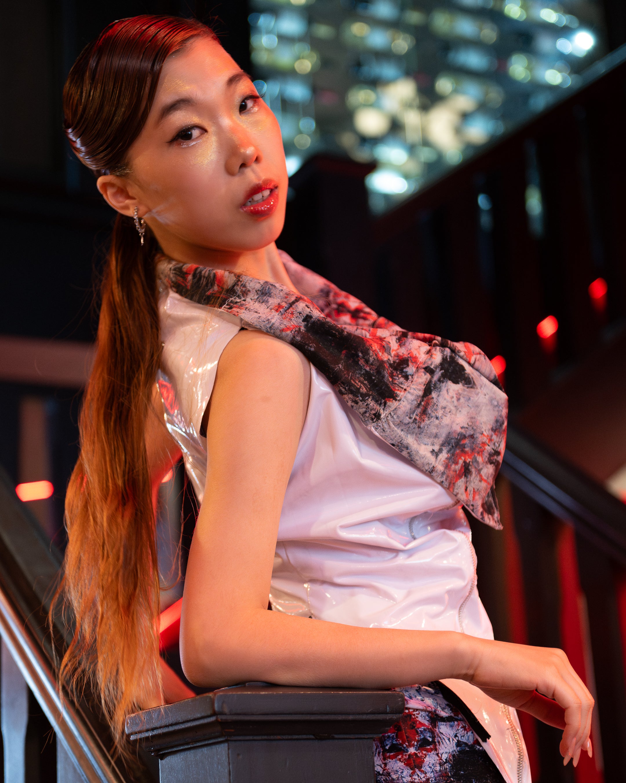 Woman with a floral scarf sitting on a staircase at night.