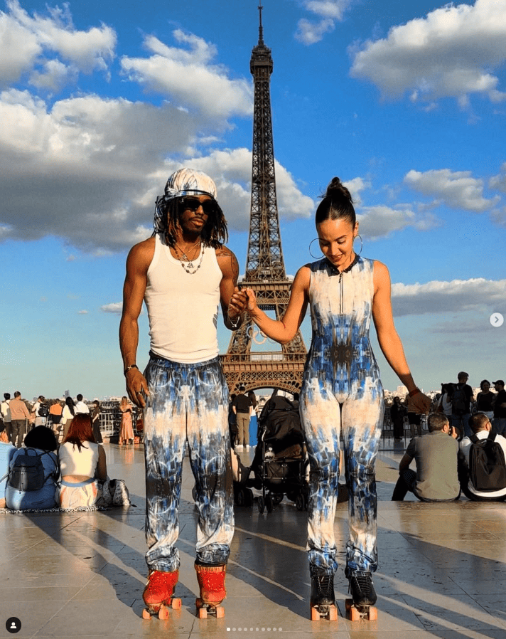 Two people in matching outfits standing in front of the Eiffel Tower.